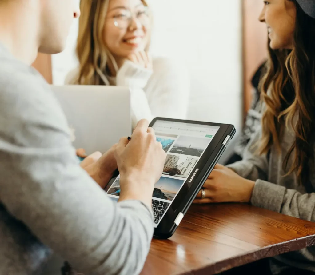 Groupe de jeunes adultes discutant autour d’une tablette Samsung, illustrant la dynamique d’un créateur d’entreprise à l’étranger en phase de lancement ou d’étude de marché à l’international.