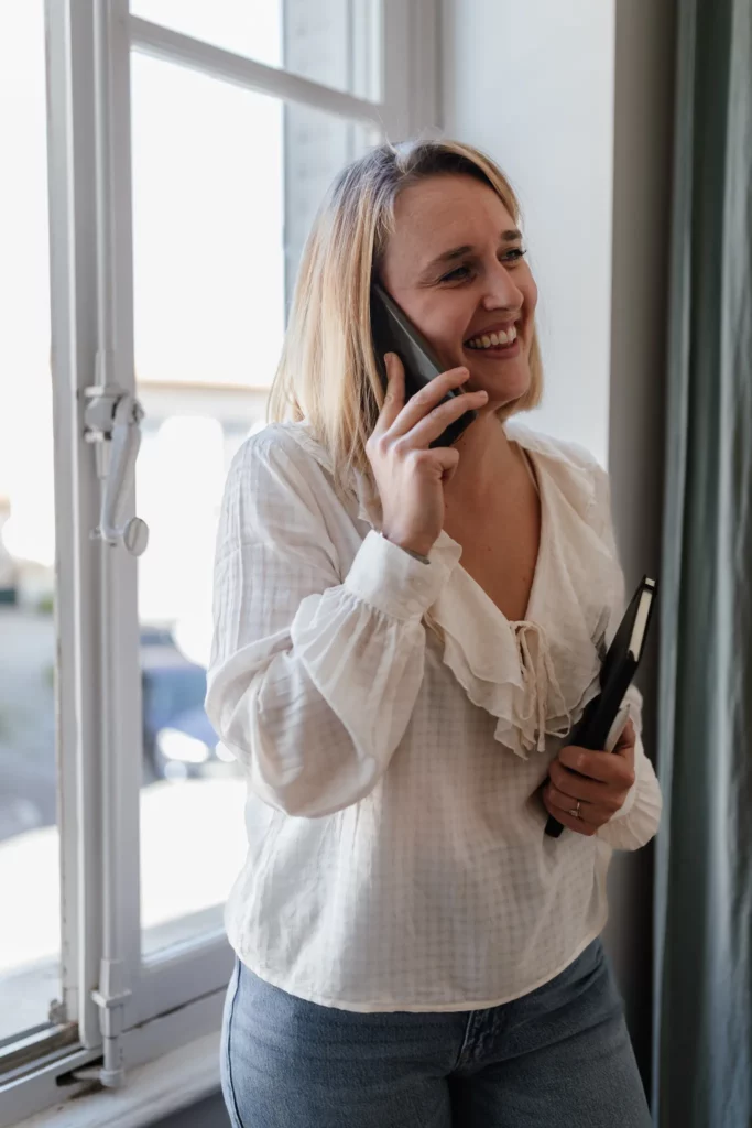 Fondatrice de Comptagency au téléphone dans son bureau, souriante et professionnelle, illustrant la proximité et l’accompagnement personnalisé du cabinet d’expertise comptable.